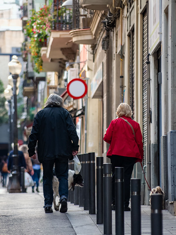 Older couple walking dog uphill on Barcelona street