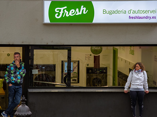 Man smoking at distance from woman in white coat outside laundromat