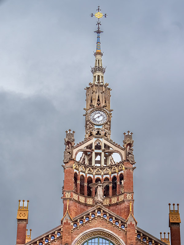 Ornate church with brass cross at peak and angel on roof