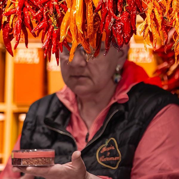 Woman half-hidden by peppers in Barcelona marketplace