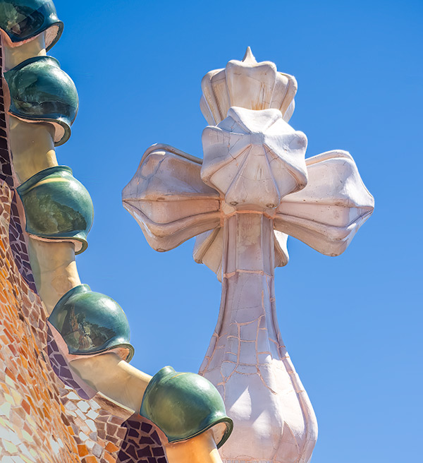 Unusual shaped cross sculpture on roof of Gaudi designed house in Barcelona.