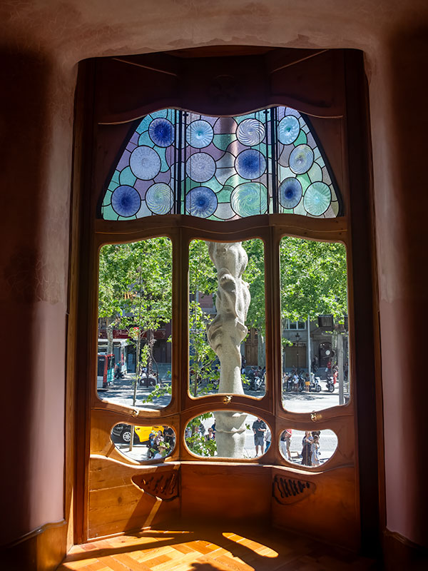 Unusual shaped wooden window in Gaudi designed house looking out to Barcelona street