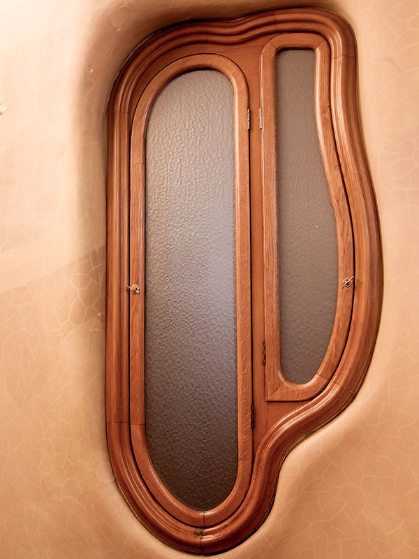 Unusual shaped, internal, wooden window inside Gaudi designed house in Barcelona