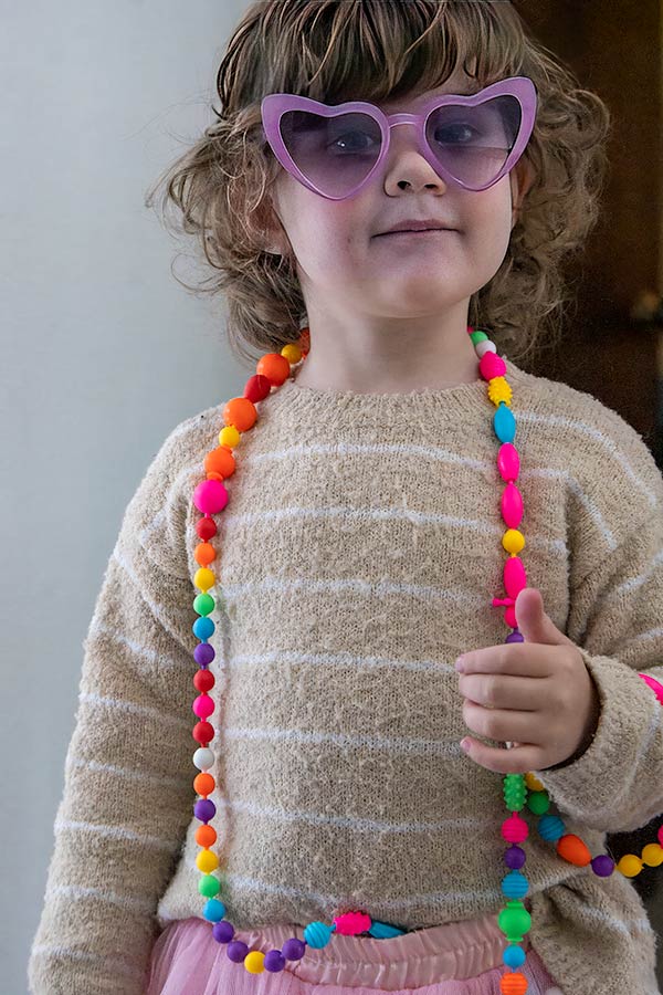 Four-year old with heart-shaped sunglasses and colorful beads
