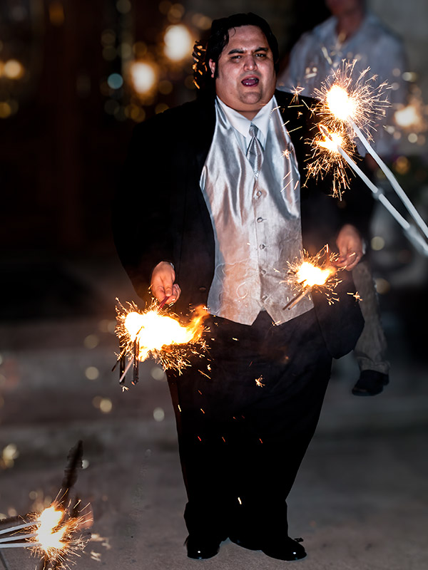 Happy man in wedding tuxedo holding sparklers